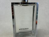 the bottle of cologne is sitting on a white surface