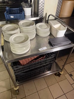many plates and bowls on a metal cart in the kitchen