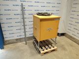 une image représentant une caisse jaune posée sur une palette devant un mur