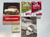 three books on a table with a car in the background