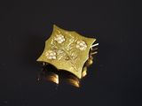 broche plaquée or jaune, ornée de fleurs et de perles sur un fond noir