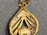 a close up of a gold pendant with a cat inside of it