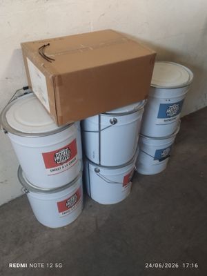 several buckets of white paint sitting next to a box on top of a cement floor