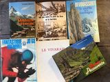several books on a wooden table with mountains in the background