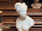 un buste de femme posé sur une table, à côté d'un vase