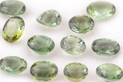 des tourmalines vertes sur une surface blanche, avec un fond blanc