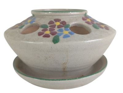 a white vase with flowers on it on a saucer