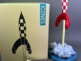 a toy rocket sitting next to a box and a card