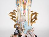 a figurine of a woman sitting on top of a vase