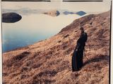 a woman that is standing on a hill by the water