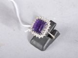 an image of a ring with a purple stone surrounded by diamonds