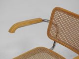 a wooden chair with a wicker seat and arm rest