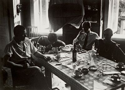 many people sitting around a table eating and drinking