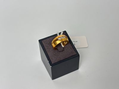 une bague en or dans un écrin noir posé sur une surface blanche