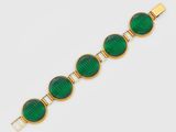 un bracelet en or orné de perles de verre vertes sur fond blanc