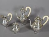 four pieces of silver tea and coffee set on a grey background