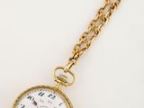 un gros plan d'une montre de poche en or attachée à une chaîne