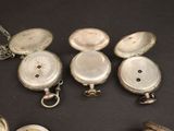 quatre types différents de montres de poche en argent posées sur une table