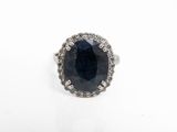 une bague ovale sertie d'un saphir et de diamants sur fond blanc