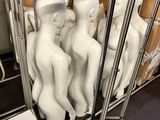 de nombreux mannequins blancs assis sur un chariot dans une pièce