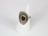 a close up of a silver ring with a red stone in it