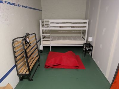 a bunk bed in the corner of a room with a red blanket on the floor