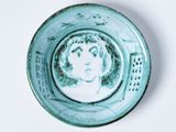 une petite assiette bleue sur laquelle est représentée une femme