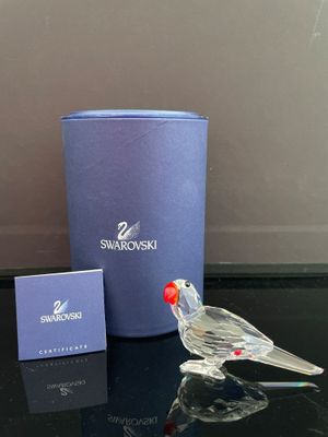 un petit oiseau en verre posé sur une table, à côté d'une boîte bleue