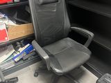 une chaise de bureau noire placée devant une bibliothèque