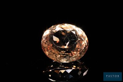 un diamant jaune sur une surface noire, avec un reflet