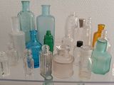 many different colored glass bottles on a glass shelf