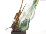 une sculpture en verre représentant un violon et un violoniste, posée sur un socle en marbre