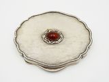 a close up of a silver plate with a red stone in it