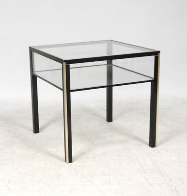 une photo d'une table d'appoint en verre et en laiton sur fond blanc