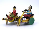 two figurines of a man and a woman riding in a toy car