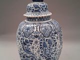 a blue and white vase with a bird on top of it