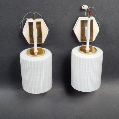 two white lamps with gold trims on a black background