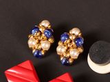 two pairs of red, white, and blue earrings and a black object on a black surface