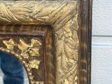 a mirror with a gold frame and a person standing in front of it