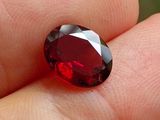 une personne tient un diamant rouge dans la main, sur un fond vert