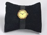 un petit oreiller noir sur lequel est posée une montre jaune