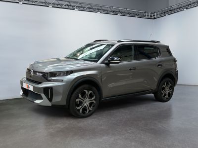 Le SUV gris est garé dans une grande pièce aux murs blancs.