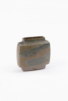 un petit vase posé sur une surface blanche