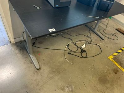 une table noire sur laquelle se trouvent deux ordinateurs, dans une pièce