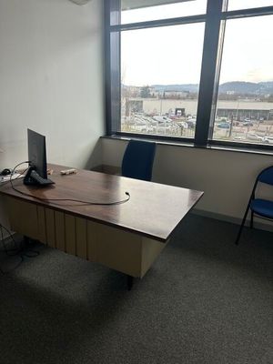un bureau sur lequel se trouve un ordinateur, avec une chaise placée devant une fenêtre