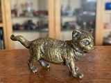 figurine en laiton représentant un chat, posée sur une table devant une bibliothèque