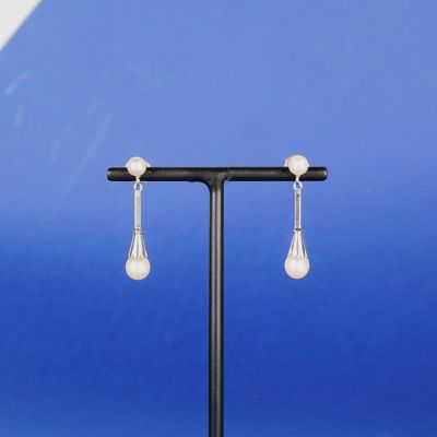 une paire de boucles d'oreilles en perles posée sur un présentoir devant un fond bleu