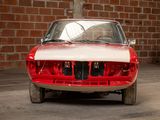 a red and white car parked in front of a brick wall