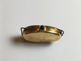a small gold plate with a blue stone in it