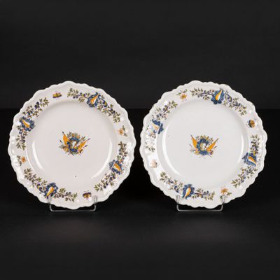 two white plates with blue and yellow designs on them on a black surface